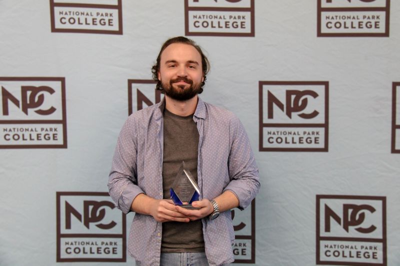 Tylor Clark holding the 2026 NPC Outstanding Staff Member Of The Year award.