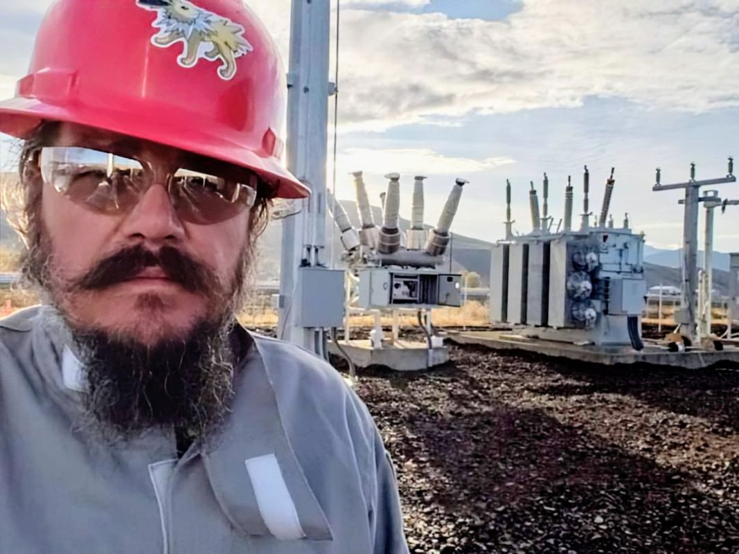 Clayton Fagan wearing a hard hat in front of industrial power station.