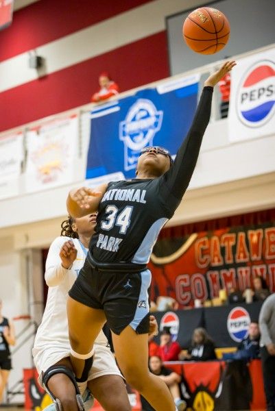 Two women playing basketball one jumping up to get the ball.