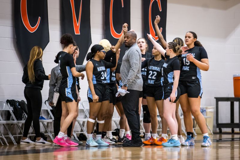 NPC women's basketball team with arms extended in the air.